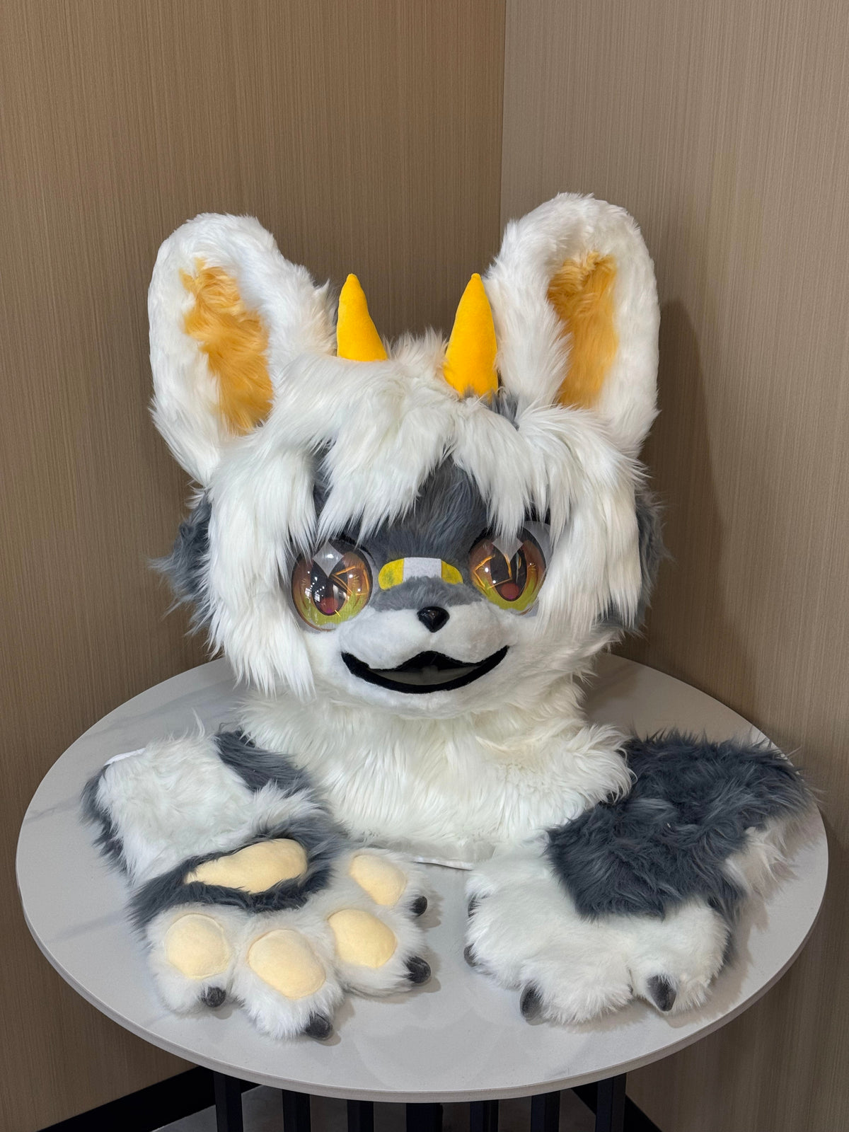 White and grey canine fursuit head with matching hand paws and gold horns